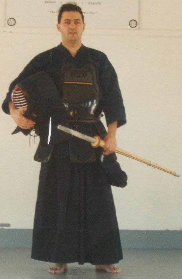 Frank Paolino Jr. in full kendo armor, holding his men helmet and a shinai